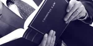 person holding a criminal law book open - Criminal defense attorney