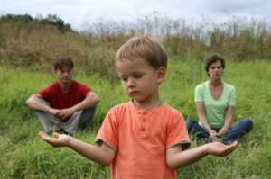 Boy holding his hands like scale choosing between his parents