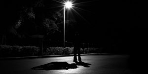 person standing under street lamp in the dark